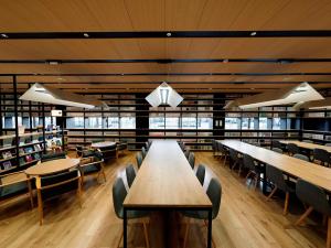 岛田HATAGO INN Shizuoka Yoshida IC的大型图书馆配有木桌和椅子