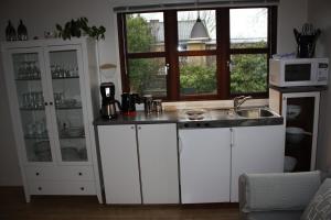 斯卡恩Skagen Ferie 1的厨房配有白色橱柜、水槽和窗户。