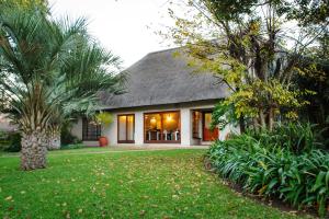肯普顿帕克Safari Club Guest Lodge OR Tambo International Airport的庭院前有棕榈树的房子