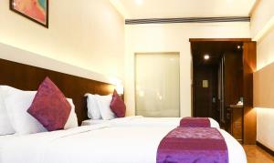 古尔冈Treebo Tryst Eden Residency的酒店客房配有两张带紫色枕头的床
