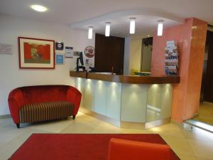 施韦夏特阿尔布切特城市酒店的一间设有柜台和红色沙发的等候室