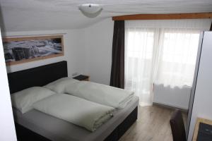 考恩台尔Haus Eckhart的一间卧室配有一张带白色床单的床和一扇窗户。