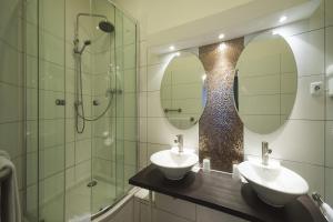 美因河畔法兰克福阿姆贝格酒店的一间带两个盥洗盆、淋浴和镜子的浴室
