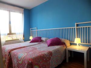 莱昂www Apartamento Conde de León wordpress com Parking opcional的蓝色卧室配有两张带紫色枕头的床
