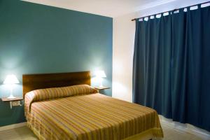 科隆布里萨斯拉戈公寓酒店的一间卧室配有一张蓝色墙壁和蓝色窗帘的床