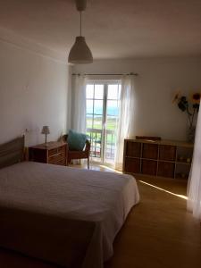 科武港Casa do Mar em Porto Covo的一间卧室设有一张床、一个窗口和一把椅子