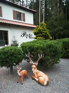TirkšliaiHotel Pušyno Namai的两座鹿雕像坐在房子旁边