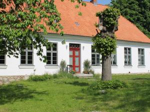 施特芬斯哈根Luxurious Apartment in Steffenshagen with Garden的白色的房子,有橙色的屋顶和红色的门