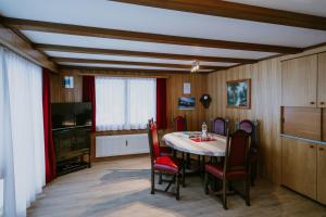 阿德尔博登阿洛亚木屋的一间带桌椅和电视的用餐室