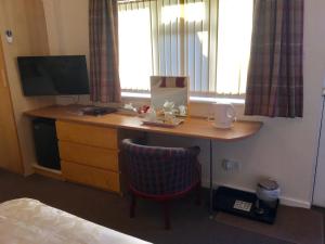 亨斯坦顿阿什莉旅舍的一张桌子,位于酒店客房内,配有电视和床