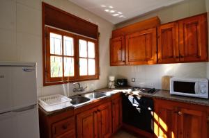 莱斯卡拉Casa la Flor的厨房配有木制橱柜、水槽和微波炉