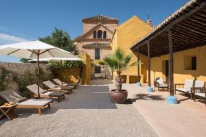 阿尔沃洛特Hotel Cortijo del Marqués的一座带椅子和遮阳伞的庭院以及一座建筑