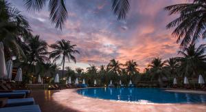 美奈蓝色大海度假酒店的棕榈树和日落的度假村游泳池