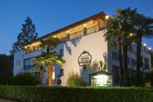 阿斯科纳阿斯科迷人别墅酒店的一座白色的大建筑,前面有棕榈树