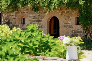 Saint-Quay-PerrosManoir des petites bretonnes的一座石头建筑,在院子里放着一束鲜花
