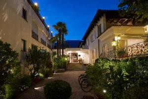 阿斯科纳阿斯科迷人别墅酒店的一座建筑的庭院,晚上有棕榈树