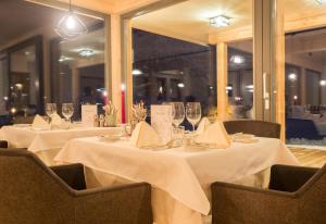 魏森湖Das Leonhard - Naturparkhotel am Weissensee的用餐室设有2张桌子、白色桌布和酒杯