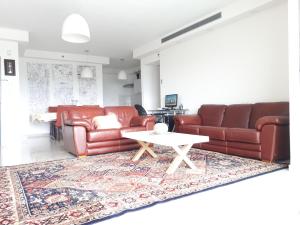 阿什杜德Shave Tsion Apartment in the center Ashdod的客厅配有2张棕色皮沙发和1张桌子