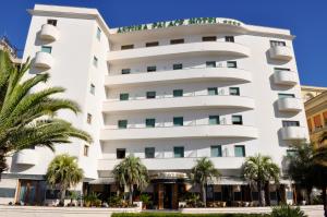 内图诺阿斯图拉宫酒店的一座白色的大建筑,前面有棕榈树