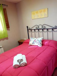 莫纳奇尔鲁塔德尔浦尔斯克营地酒店的粉红色的床,上面有两条毛巾和鞋子