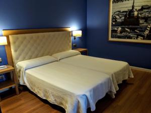 San Carlos del ValleHospedería Santa Elena的卧室配有白色大床和蓝色的墙壁