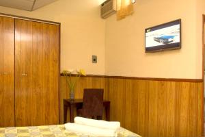 圣萨尔瓦多Hotel Manantiales El Salvador的一间设有床铺和墙上电视的客房