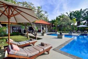 Banjar萨夫兰别墅的一个带2把躺椅和遮阳伞的度假游泳池
