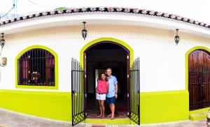 莱昂Casa Lula León Hostal的两个人站在一个黄白色房子的门廊上