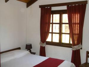 拉帕洛马阿迪雅迪娜卡瓦尼亚斯酒店的一间卧室配有床和红色窗帘的窗户