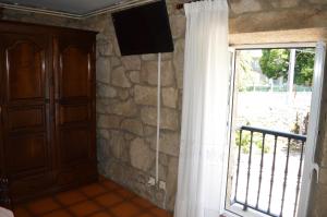 卡尔达斯·德·雷斯Casa Loureiro的一间设有窗户的客房,并在石墙上配有电视