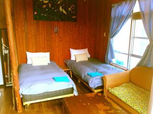 宫古岛都岛宾馆的一张沙发和一个窗户的客房内的两张床