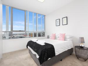 悉尼As the Sun Sets - Modern and Spacious 2BR Zetland Apartment Facing the Setting Sun的白色卧室设有床和大窗户