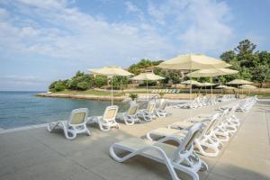 弗尔萨尔Maistra Select Petalon Resort的水边的一排白色椅子和遮阳伞