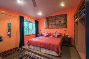 奥克兰大庞森比艺术住宿加早餐旅馆的一间卧室拥有橙色的墙壁,床上铺有红色床单。