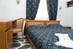 加利萨斯马努索斯客房酒店的一间卧室配有一张床、一张书桌和一个窗户。