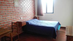 乌尤尼Piedra Blanca Backpackers Hostel的一间卧室设有一张床和砖墙