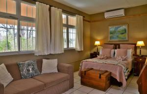 ChobeMuchenje Self Catering Cottages的一间卧室配有一张床、一张沙发和窗户。