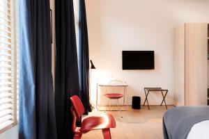 安特卫普朱利安酒店的一间卧室配有一张床、一把椅子和电视