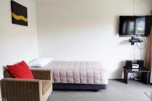 惠灵顿马克斯曼汽车旅馆的一间卧室配有一张床、一把椅子和电视。