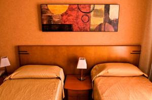 阿哈尔维尔Hostal Villa de Ajalvir的一间卧室配有两张床和一张带台灯的桌子