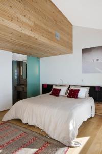 Villaroger矿产旅馆及水疗中心的卧室配有带红色枕头的大型白色床