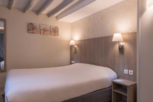 巴黎西部酒店的酒店客房设有一张大床和两盏灯。