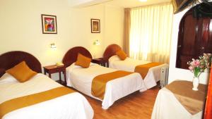 库斯科Hotel Vilandre的一间酒店客房,配有三张床和鲜花