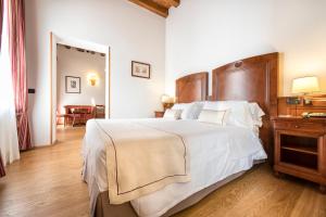 卡斯泰尔达扎诺玛拉斯皮娜别墅酒店的卧室配有一张白色大床和木制床头板