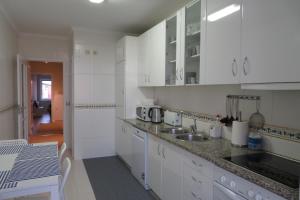 Vila ChãLenda do Mar的厨房配有白色橱柜、水槽和桌子
