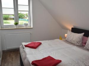 格罗斯施旺湖Cozy Holiday Home in Gross Schwansee with Sauna的卧室配有白色床和红色毛巾