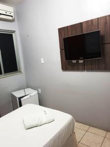 MaracanaúPousada das Maracanãs的卧室配有一张床和壁挂式平面电视。