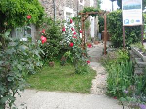 康卡勒Appartements Couleurs de Mer CANCALE的一座花园,花园内种植了红色玫瑰,一座建筑