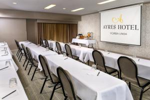 安纳海姆约巴林达/阿纳海姆山艾瑞斯套房酒店的一间会议室,配有白色的桌椅和屏幕