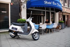 阿姆斯特丹弗里斯科酒店的停在餐厅前的摩托车,有位女士坐在桌子前